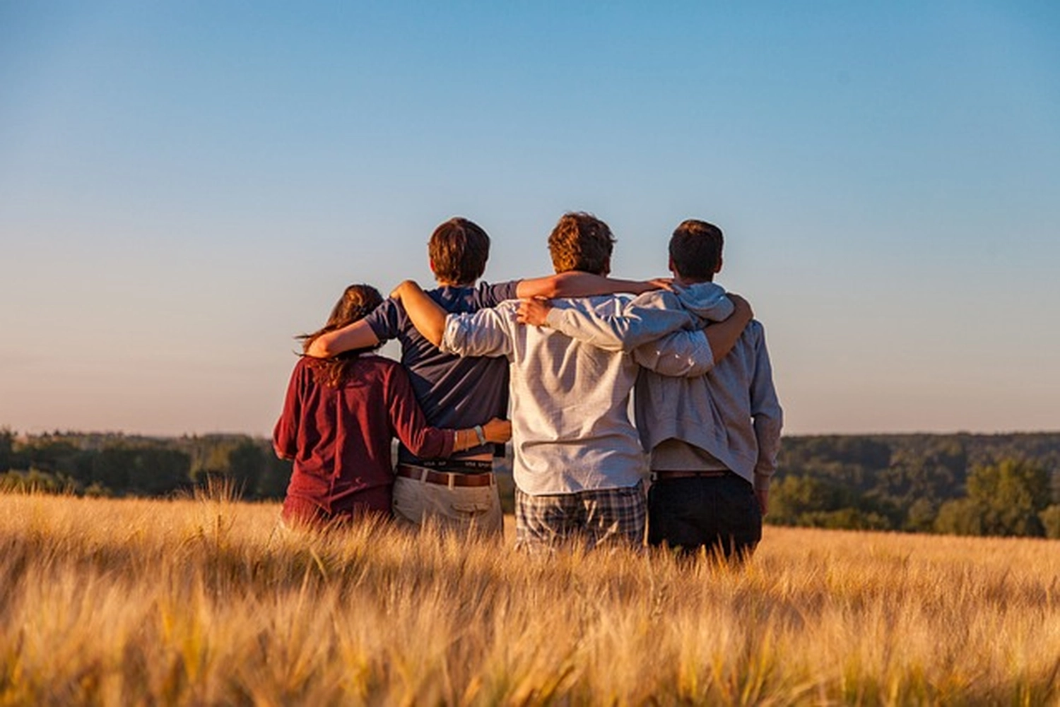 Krug & Helferin – Carmen Krug – Kinder- und Jugendhilfe – Vier Personen sitzen zusammen auf einem Feld